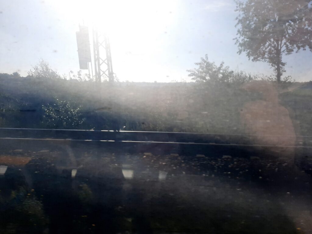 Blick aus einem dreckigen Zugfenster in die Landschaft