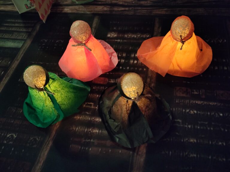 Vier kleine selbstgebastelte Figuren, die wie Magier aussehen. Von innen heraus beleuchtet.