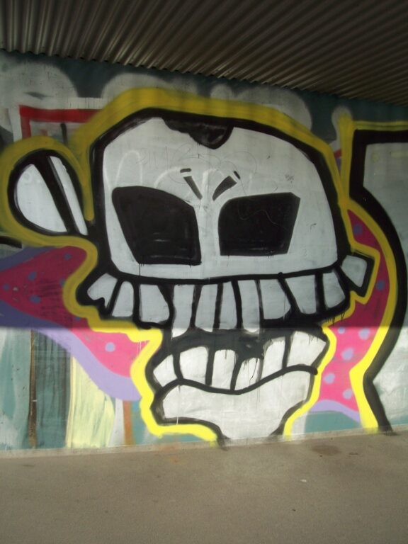 Street-Art: Graffiti eines Totenkopfes, unter eine Brücke gesprayt.