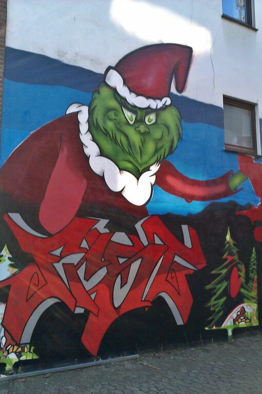 Street-Art: Der Grinch als Graffiti an einer Hausmauer.