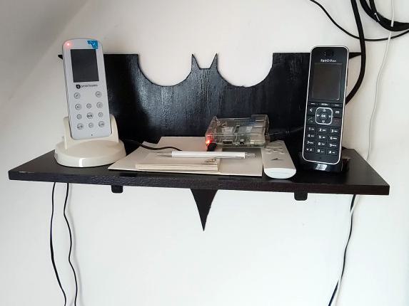Fertig montiertes Batmanregal, an einer Wand befestigt. Darauf steht unter anderem ein Telefon.