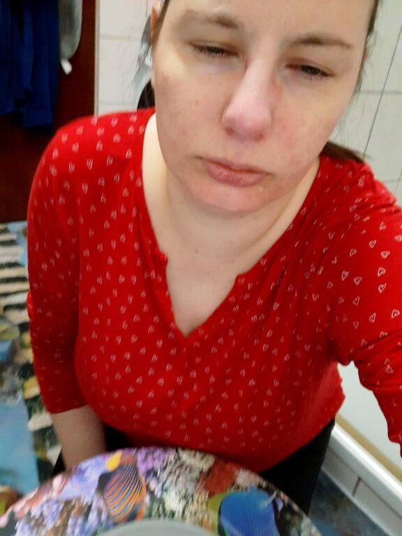 Selfie einer Frau (Ros) mit Migräne, vor einer Toilettenschüssel kniend