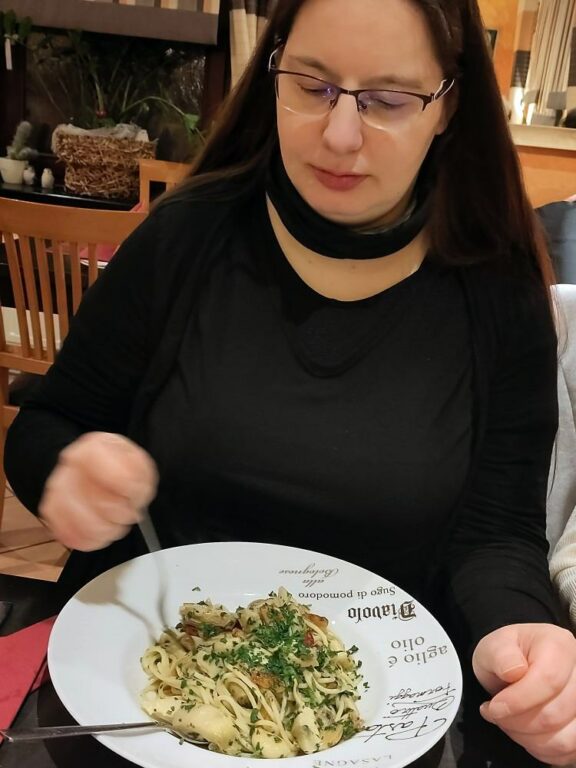 Eine Frau mittleren Alters (Rosi), dreht Spaghetti auf eine Gabel.