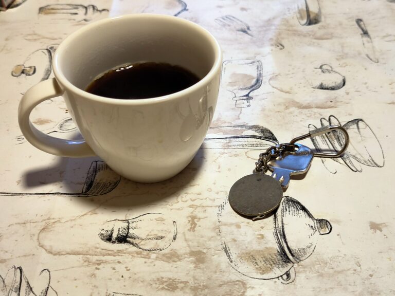 Eine halb gefüllte Tasse Kaffee daneben liegt ein einzelner Schlüssel.